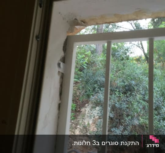 מסגרת חלון עם סורגי מתכת ונוף טבעי בחוץ